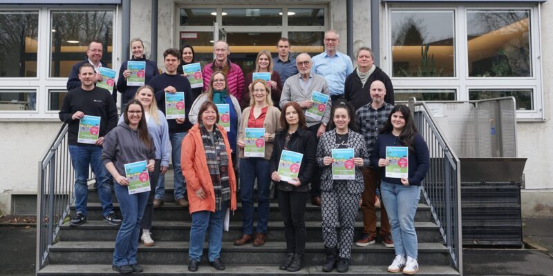 Gruppe von Frauen und Männern halten, auf der Treppe vor einem Gebäude stehend, Poster hoch.